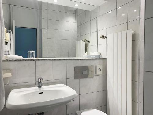a bathroom with a sink and a toilet and a mirror at Hotel Parc Belle-Vue in Luxembourg