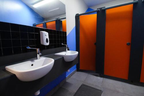 a public bathroom with two sinks and orange doors at London Backpackers Youth Hostel 18 - 35 Years Old Only in London