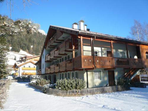 a building with a balcony on top of it in the snow at Casa El Tobià in Pozza di Fassa
