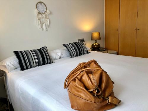a purse sitting on top of a white bed at Sun d'Aro in Platja d'Aro