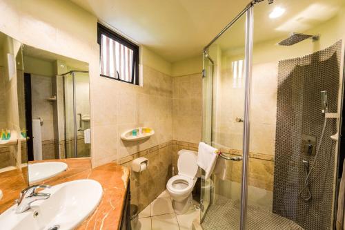 een badkamer met een wastafel, een toilet en een douche bij Cassia Lodge in Munyonyo
