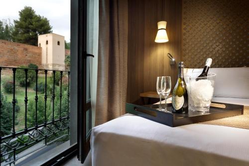 a room with a bed and a window with wine bottles and glasses at Áurea Washington Irving by Eurostars Hotel Company in Granada