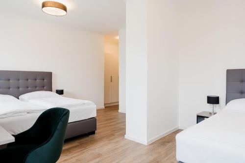 1 Schlafzimmer mit 2 Betten und einem grünen Stuhl in der Unterkunft Müllner Smart Hotel Wien Self Check In in Wien