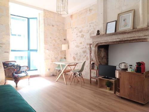 uma sala de estar com uma televisão e uma mesa com cadeiras em B&B Bordeaux Saint Michel em Bordeaux