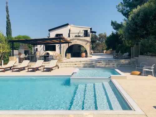 a swimming pool with chairs and a house in the background at The Goathouse in Larnaka