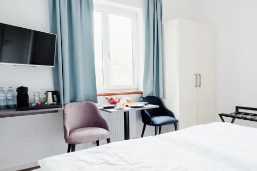 a bedroom with a table and two chairs and a bed at Müllner Smart Hotel Wien Self Check In in Vienna
