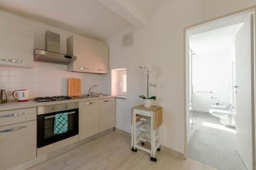 cocina blanca con fogones y fregadero en CASA ROSA- Appartamento nel verde con posto auto, zona tranquilla,wifi gratuito,aria condizionata, en Rapallo