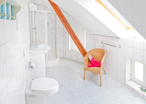 a bathroom with a toilet and a chair with a pink pillow at Pension Hanna in Bad Wilsnack