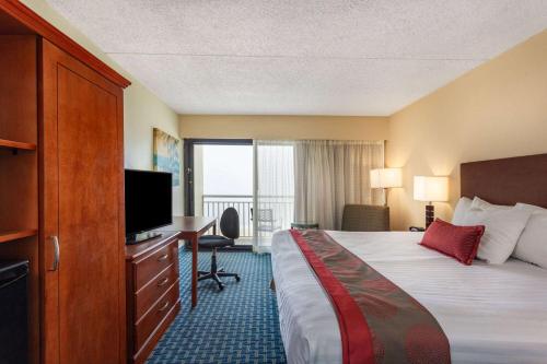 a hotel room with a bed and a desk and a television at Ramada Plaza by Wyndham Virginia Beach Oceanfront in Virginia Beach