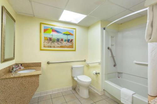 a bathroom with a toilet and a tub and a sink at Ramada Plaza by Wyndham Virginia Beach Oceanfront in Virginia Beach