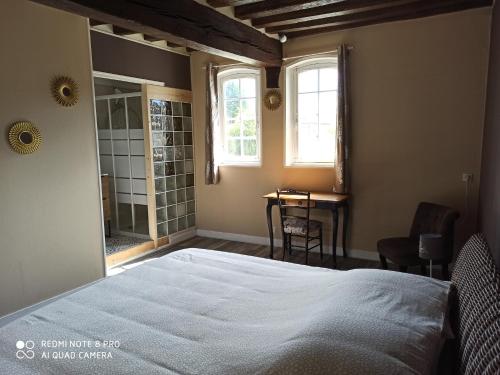 a bedroom with a large bed and a bathroom at La Colombine in Vascoeuil