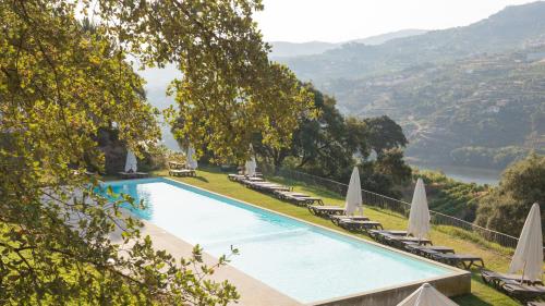 a swimming pool with lawn chairs and umbrellas at Douro Palace Hotel Resort & SPA in Baião