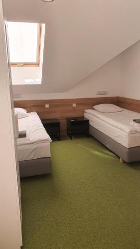 two beds in a room with green carpet at Agroturystyka Na Szlaku in Święta Katarzyna