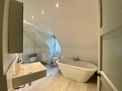 ein Badezimmer mit einer weißen Badewanne und einem Waschbecken in der Unterkunft Dunvegan Castle Gardens Cottage in Dunvegan