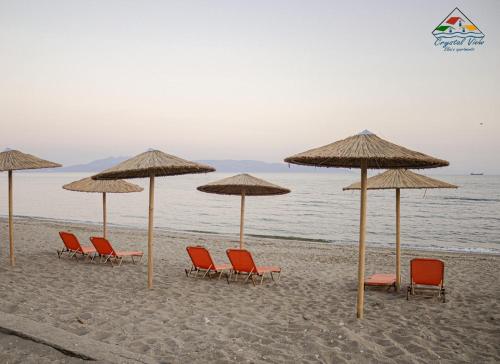 een groep stoelen en parasols op een strand bij Crystal View - Elsa's Apartments in Kavala