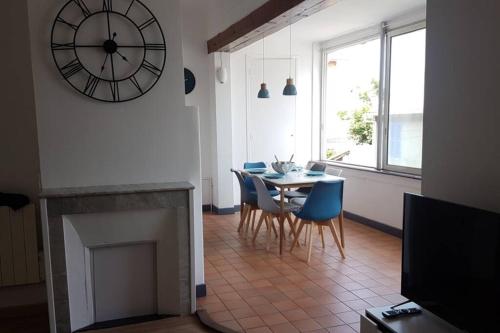 a dining room with a table and a clock on the wall at Appart hôtel plage des capucins in La Ciotat