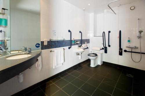 a bathroom with two sinks and a toilet and a mirror at Holiday Inn Express Leeds City Centre - Armouries by IHG in Leeds