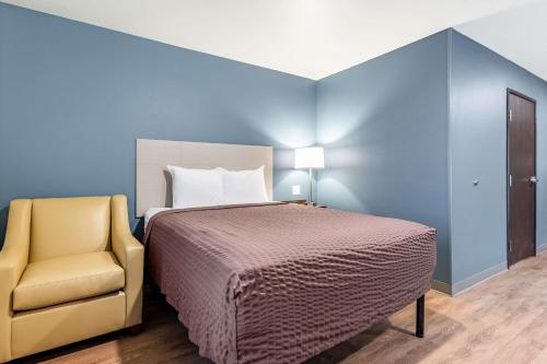 a bedroom with a bed and a yellow chair at WoodSpring Suites Indianapolis Airport South in Indianapolis