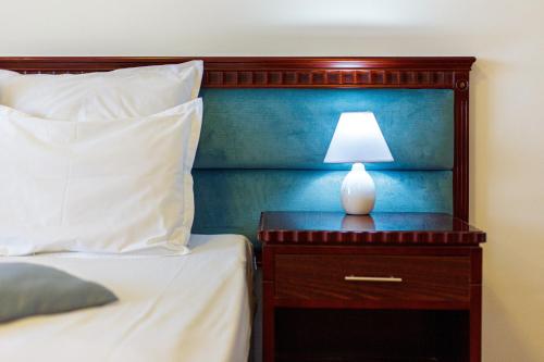 a bed with a night stand with a lamp on it at Lira Pacific Aparthotel in Constanţa