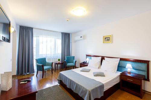 a hotel room with a bed and two chairs at Lira Pacific Aparthotel in Constanţa