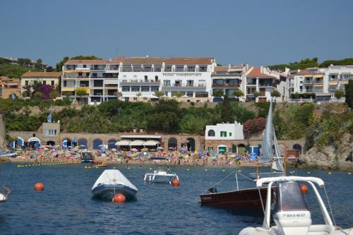 a group of people on a beach with boats in the water at Hotel Mediterrani in Calella de Palafrugell