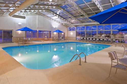 uma grande piscina com cadeiras e guarda-sóis azuis em Holiday Inn Youngstown-South - Boardman, an IHG Hotel em Boardman