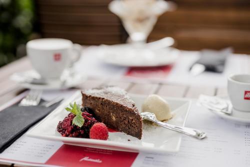 a piece of cake and berries on a plate on a table at Müllner Smart Hotel Wien Self Check In in Vienna