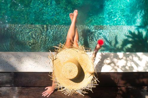 une personne dans un chapeau de paille se posant dans une piscine dans l'établissement The Mandana Villa Gili Air, à Gili Air