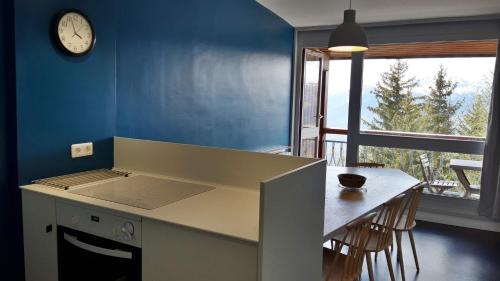a kitchen with a table and a clock on the wall at travelski home select - Résidence Thuria in Arc 1800