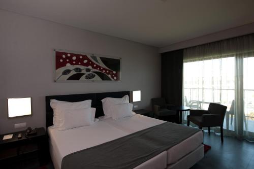 a hotel room with a bed and a desk and window at Vila Gale Lagos in Lagos