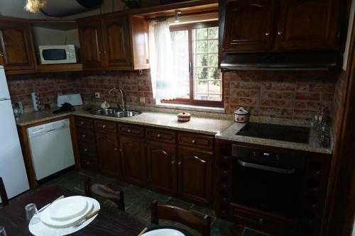 a kitchen with wooden cabinets and a sink and a window at Quinta Dos Carvalhos in Vilarinho de Agrochão
