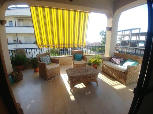 a balcony with wicker furniture and a yellow curtain at B&B Nereidi in Melito di Porto Salvo