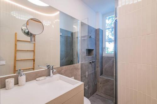 une salle de bain avec un lavabo et une douche avec un miroir dans l'établissement Côte des Basques, terrasse, confort et qualité, à Biarritz