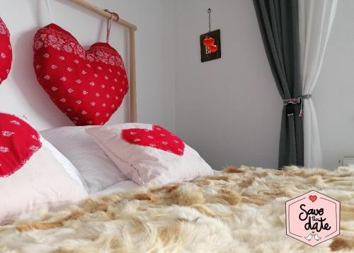 a bed with red and white pillows and two hearts at MyMara , Apartmán Ivadella in Bešeňová