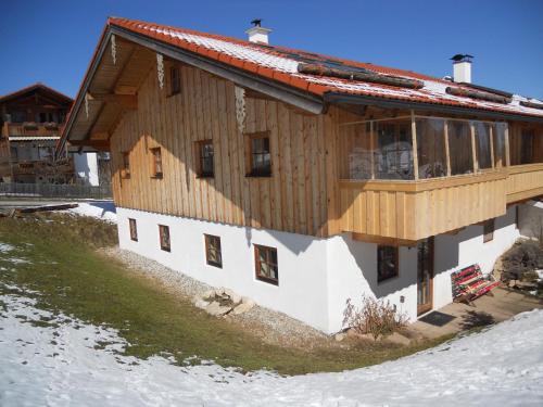 un gran edificio de madera con nieve en el suelo en Ferienwohnung Aicher Sagberg, en Frasdorf