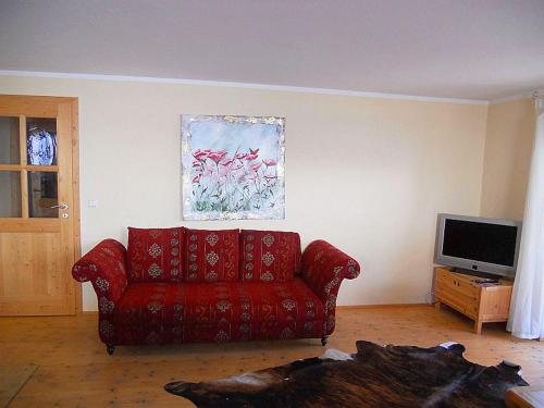 sala de estar con sofá rojo y TV en Ferienwohnung Aicher Sagberg, en Frasdorf