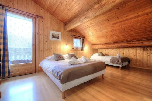 a bedroom with two beds and a large window at Chalet-Hôtel de l'Etape in Les Contamines-Montjoie