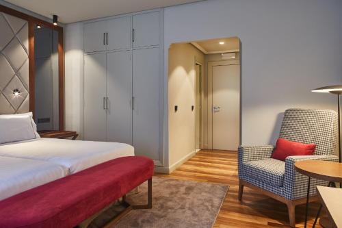a bedroom with a bed and a chair and a table at Hotel Silken Palacio Uribarren in Lekeitio