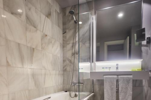 a bathroom with a shower and a tub and a sink at Hotel Silken Palacio Uribarren in Lekeitio