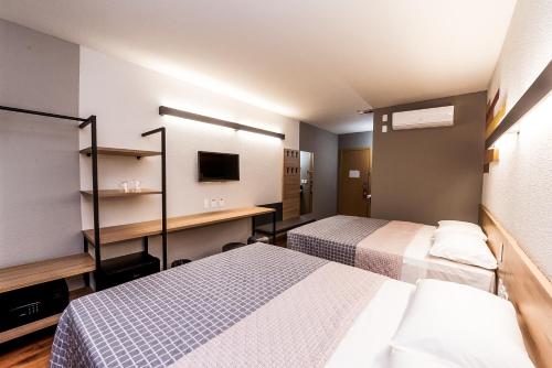 a hotel room with two beds and a desk at Hotel 10 Balsas in Balsas