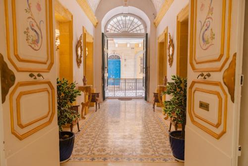 um corredor num edifício com paredes amarelas e vasos de plantas em Casa Rocca Piccola B&B em Valletta