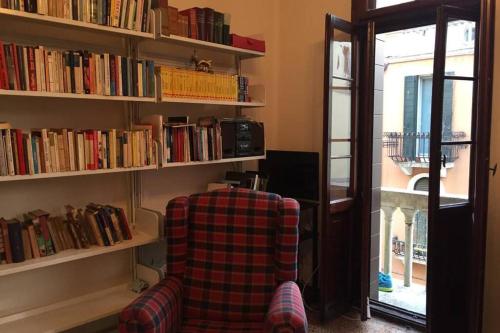 una habitación con una silla y estanterías de libros en A Casa di Claudia, en Venecia