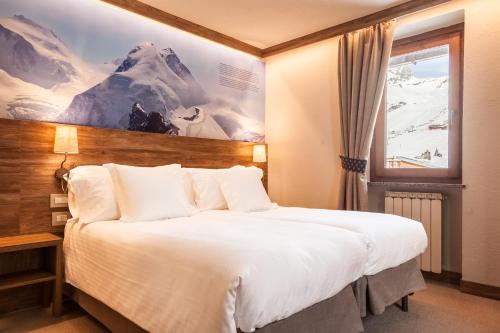 Habitación de hotel con cama grande y ventana en Hotel Breithorn, en Breuil-Cervinia