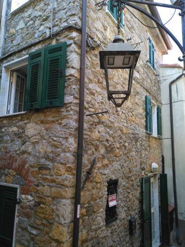 uma luz de rua ao lado de um edifício de pedra com persianas verdes em Casa Ida em Monte Marcello