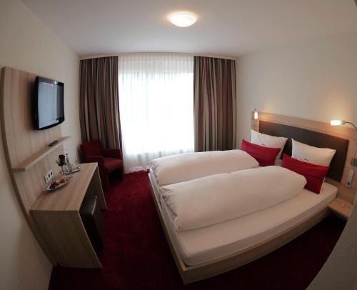 a hotel room with two beds and a television at Gästehaus Rössle in Weinstadt
