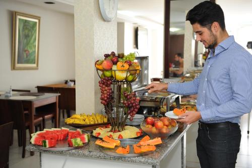 a man standing in front of a buffet of fruit at Ouro Cerrado Palace Hotel in Patrocínio
