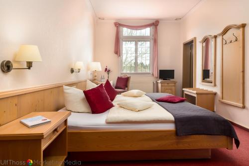 a bedroom with a large bed with red pillows at Hotel Reinhold in Gummersbach