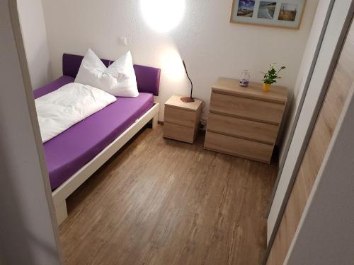 a small bedroom with a purple bed and a night stand at Appartamenti Jurahof in Däniken