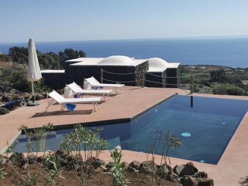 une piscine avec des chaises longues et une maison dans l'établissement Dammusi Sciuvechi, à Pantelleria
