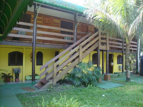 a yellow building with a wooden staircase in front of it at Pousada Mar e Cia in Ilha do Mel